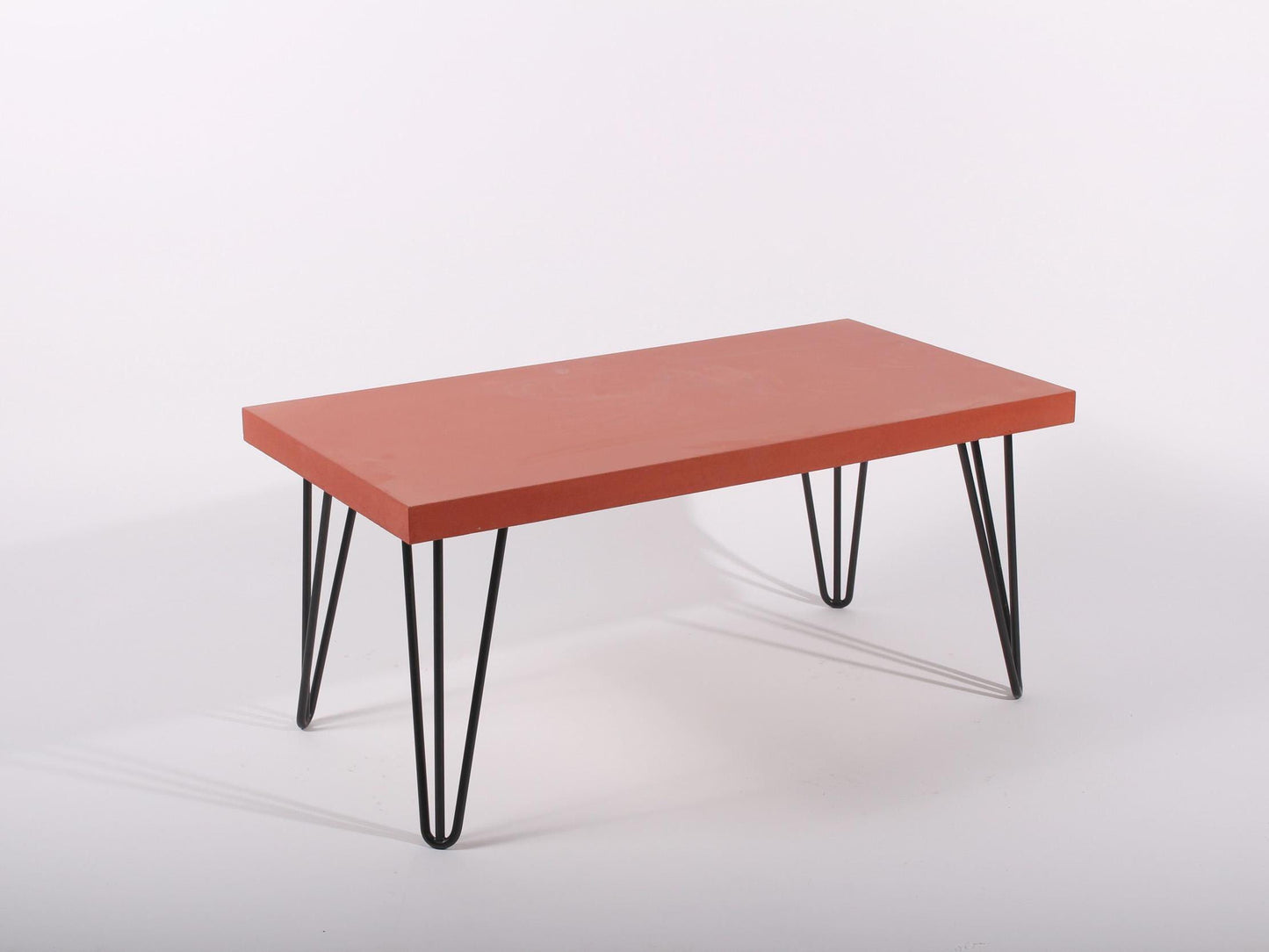 Large red concrete coffee table with hairpin legs