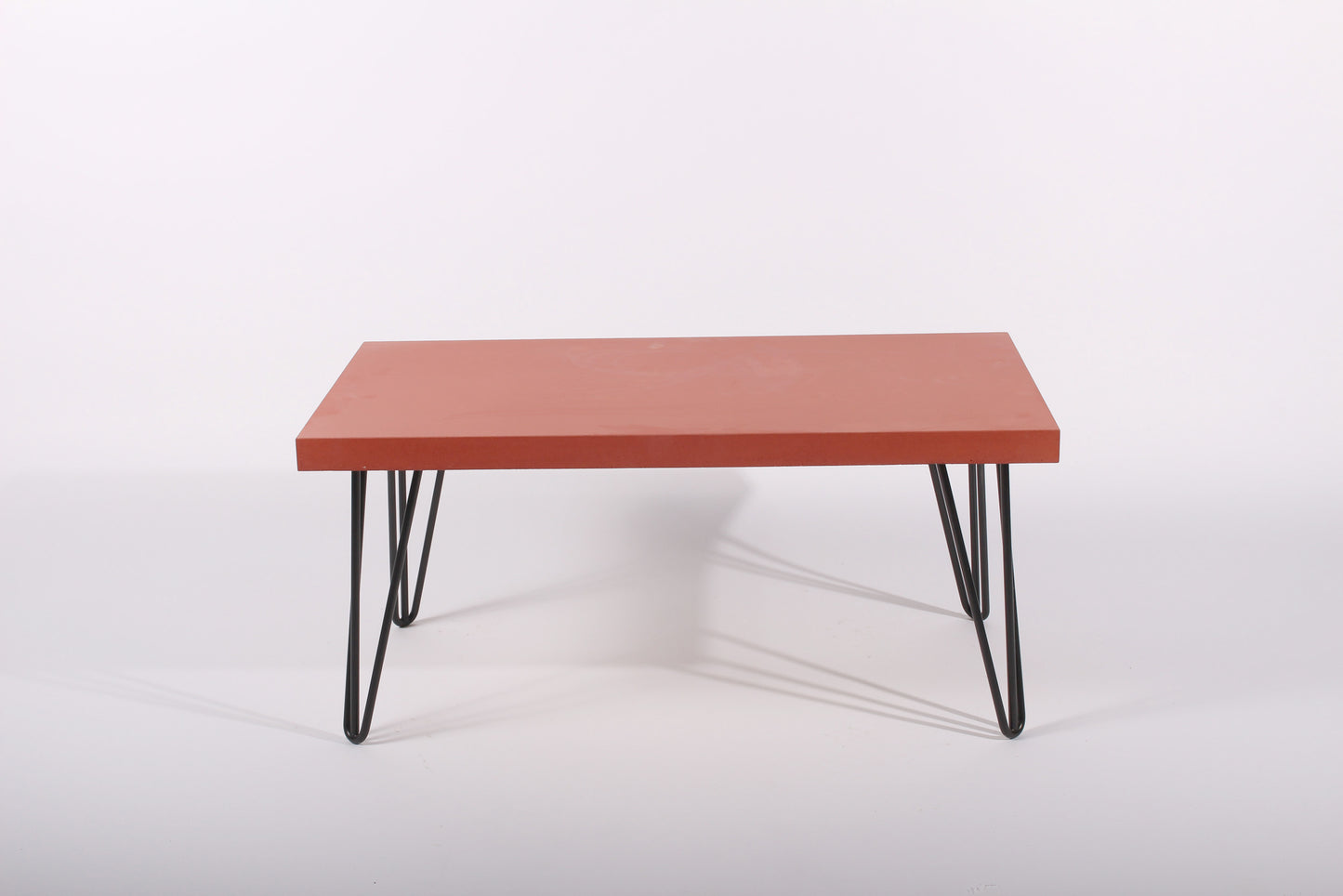 Red table with black hairpin legs on a white background