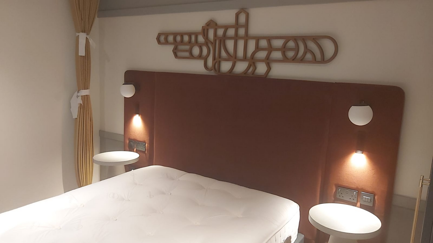 Bedroom with a large bed, decorative headboard, and wall art.