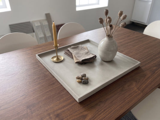 Tray with decorative items on a wooden table in a room with chairs and a radiator.