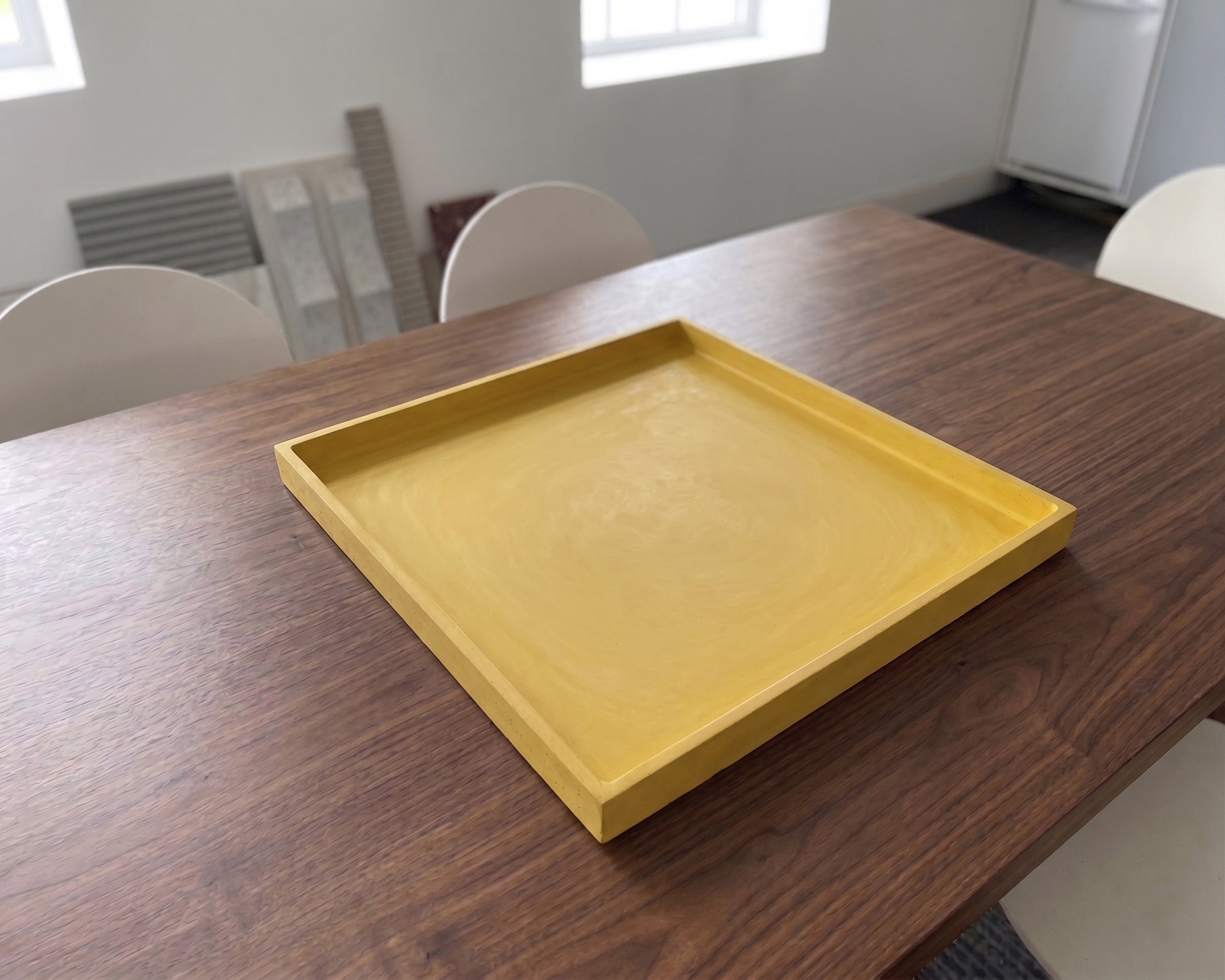 Yellow tray on a wooden table in a room with chairs and a radiator.