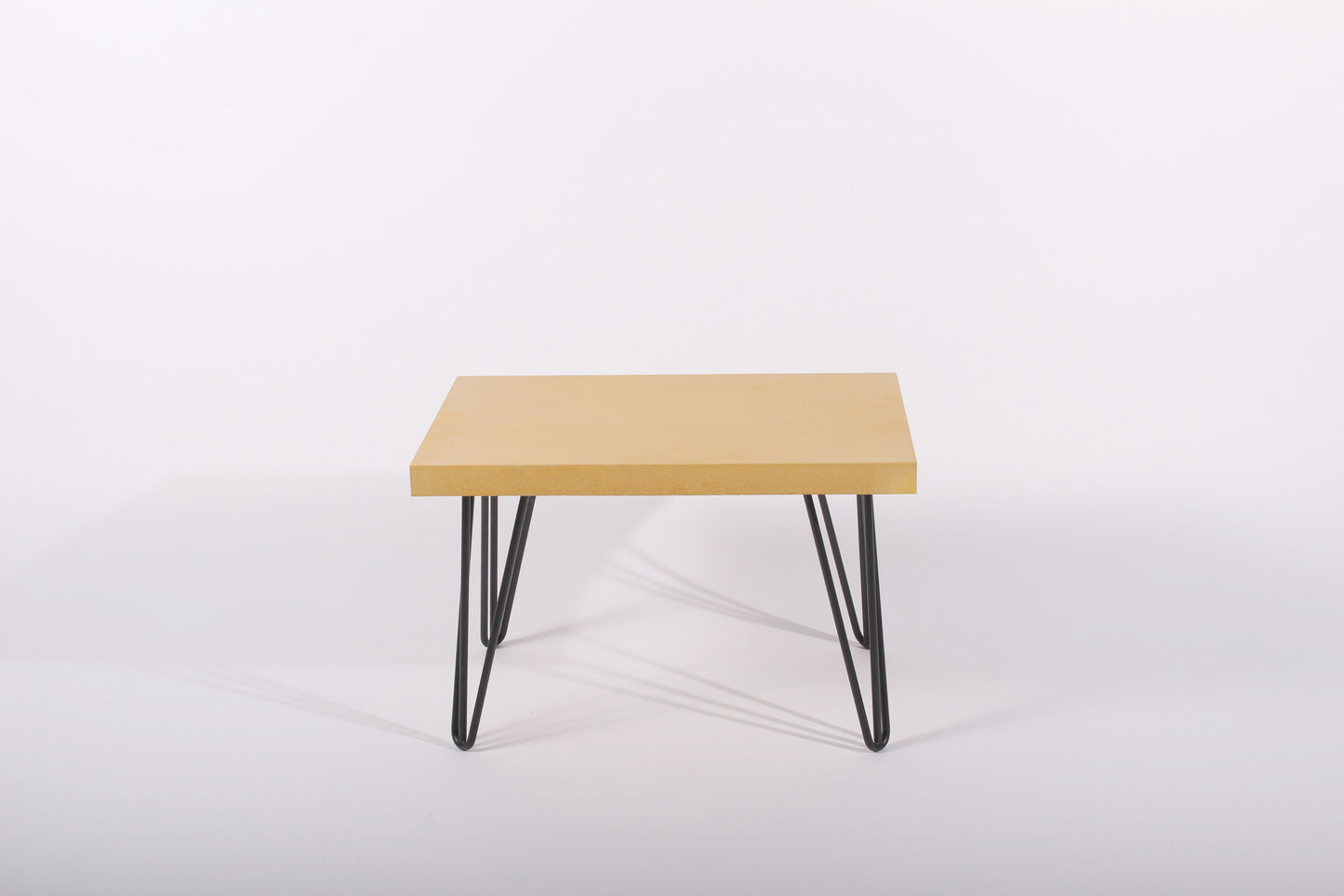 Small yellow table with black metal legs on a white background