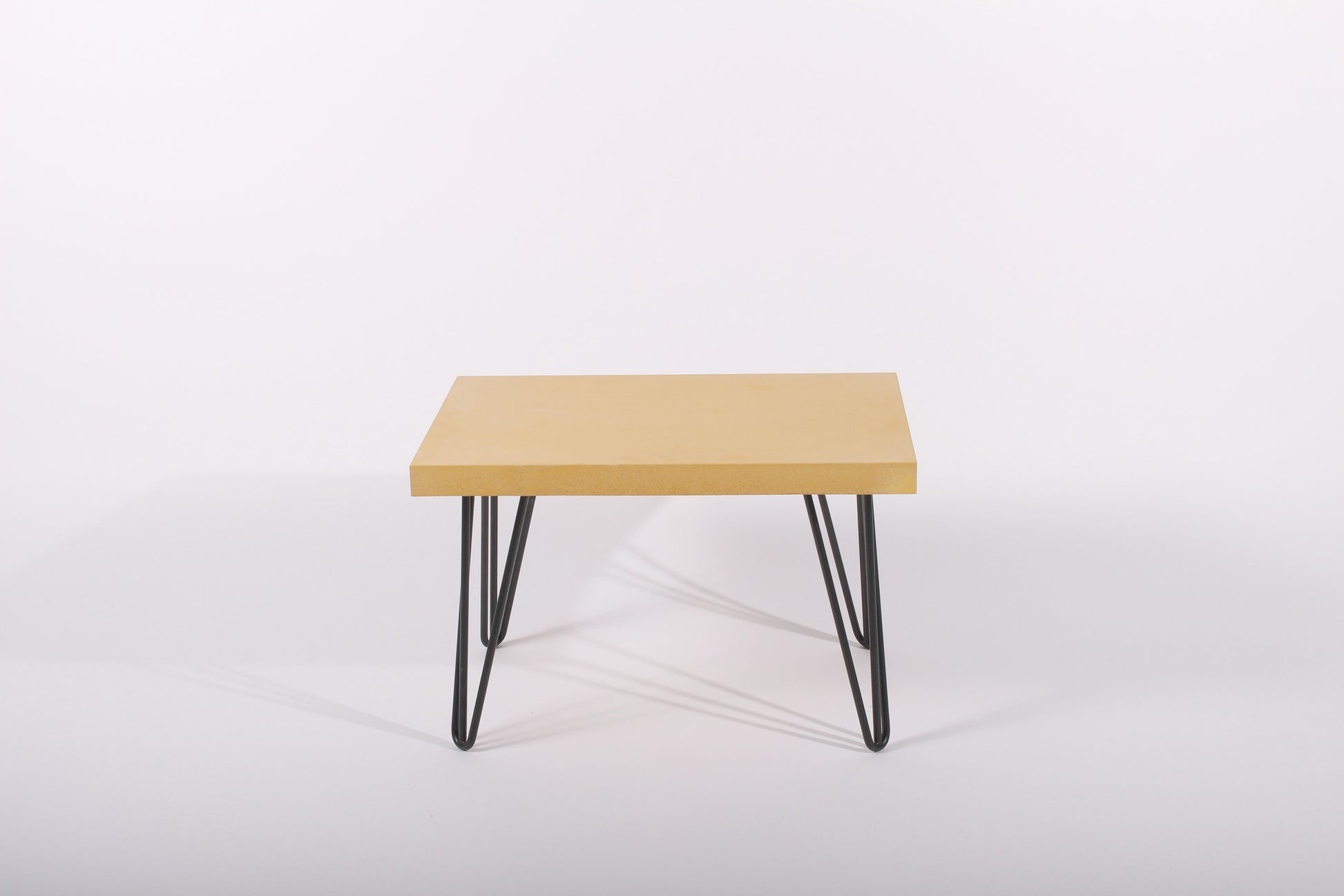 Small yellow table with black metal legs on a white background