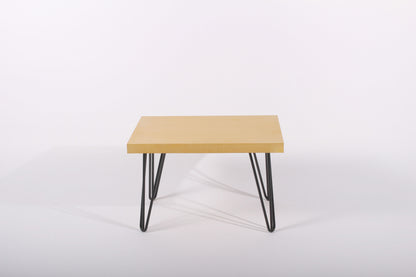 Small yellow table with black metal legs on a white background