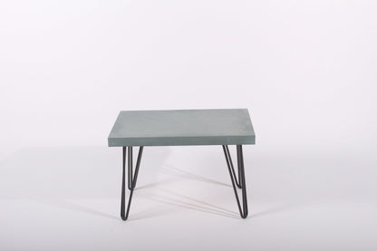 Small rectangular table with a green and blue surface and black metal legs on a white background