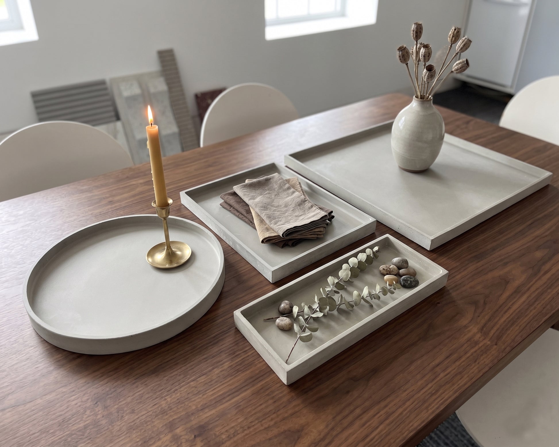 Decorative setting on a wooden table with trays, candle, and vase.