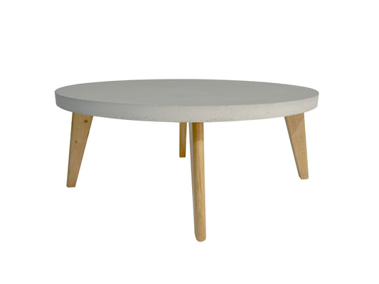 Round coffee table with concrete table top and wooden legs on a white background