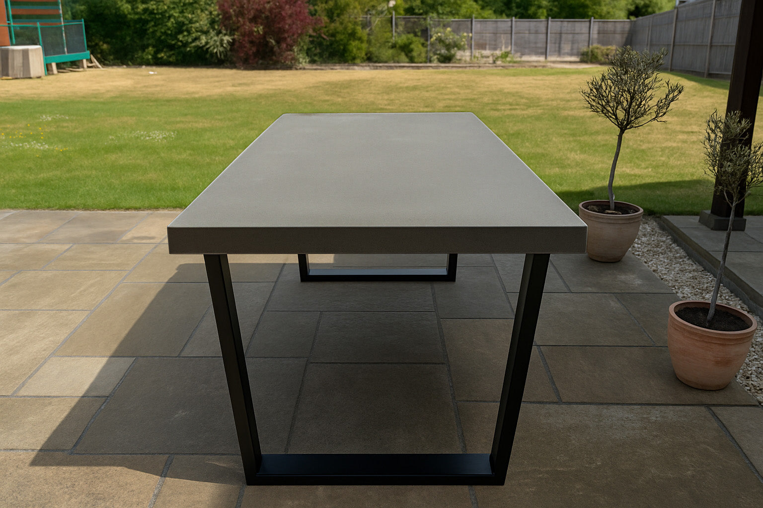 Outdoor dining table on a patio with grass and plants in the background