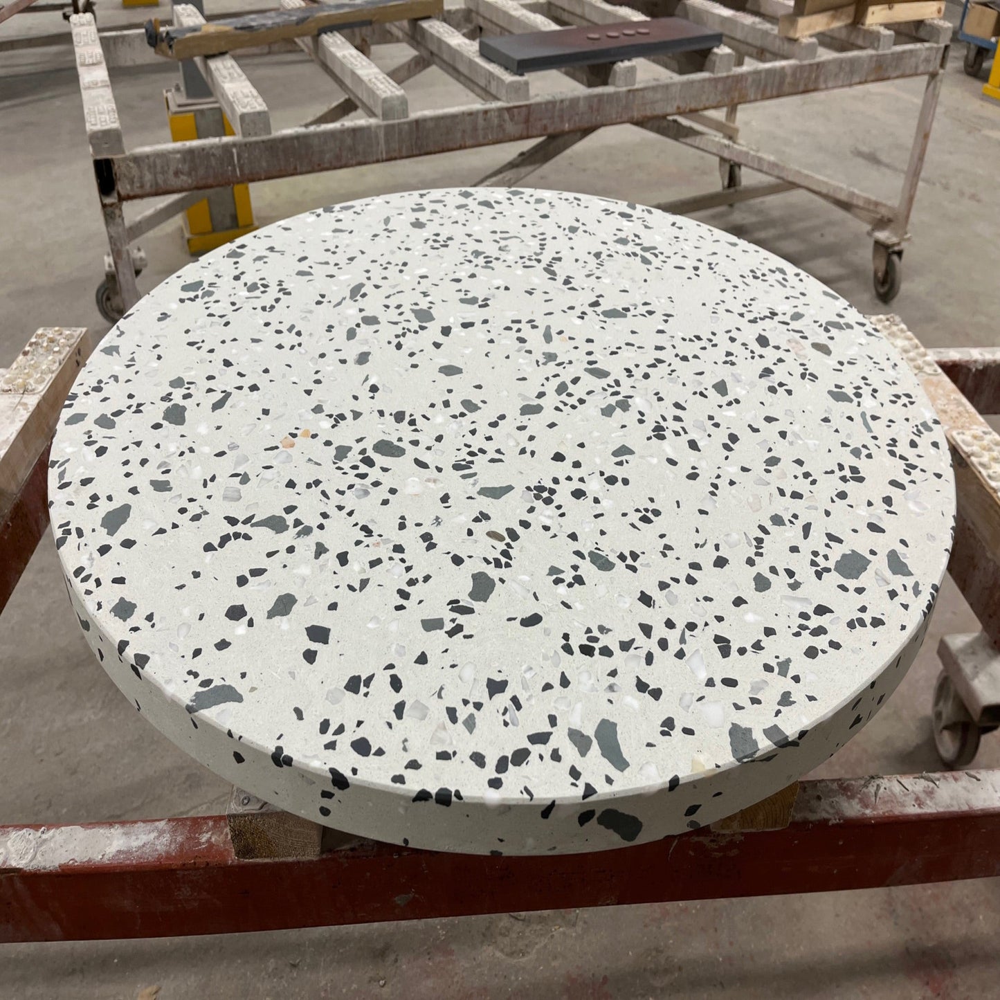 Round terrazzo table on a metal stand with a blurred background