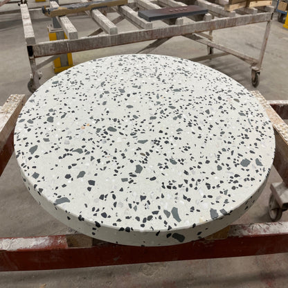 Round terrazzo table on a metal stand with a blurred background