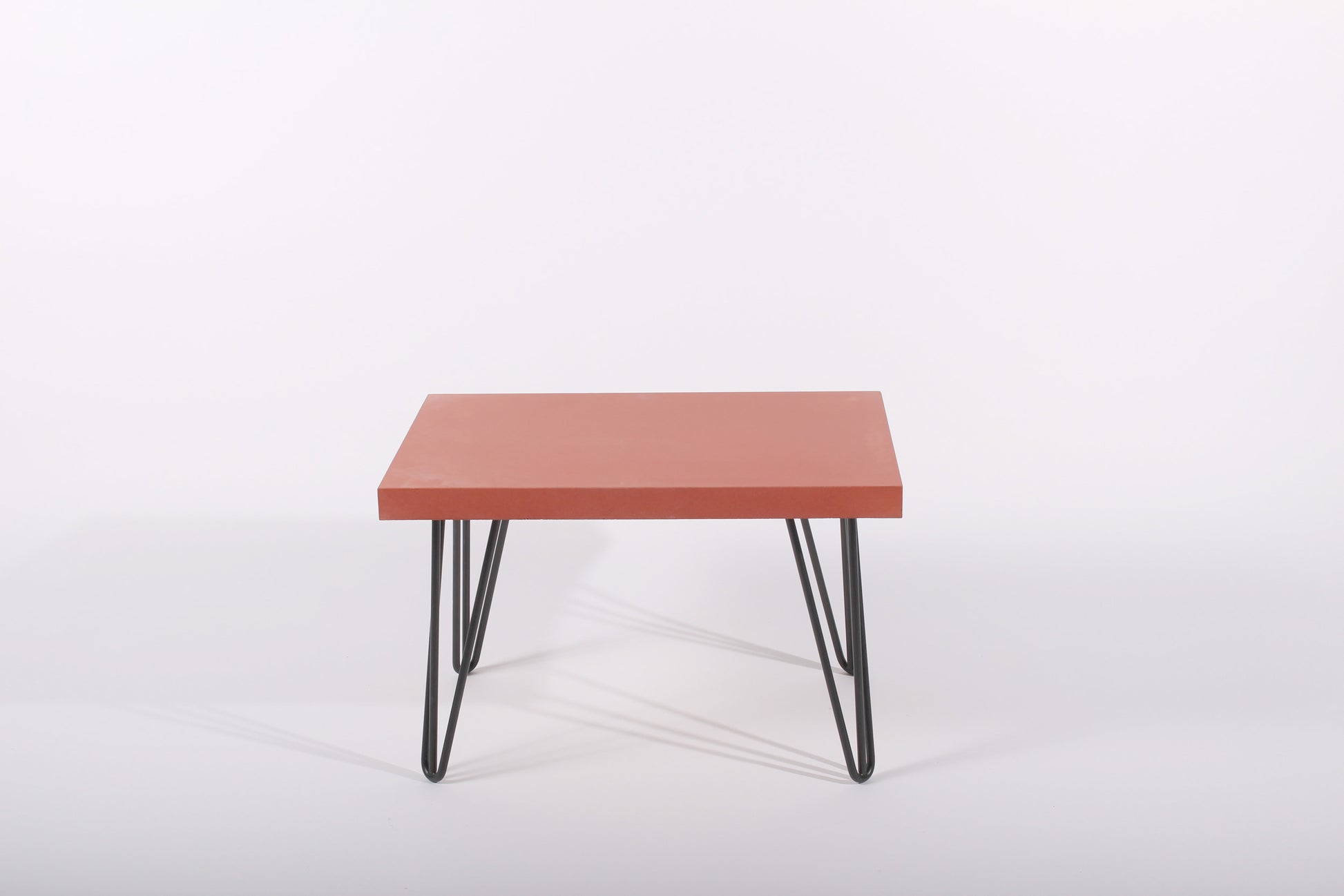 Small table with a red surface and black metal legs on a white background