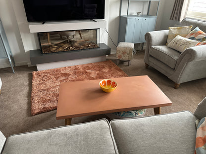 Living room with a fireplace, TV, and a bowl of fruit on a concrete coffee table.